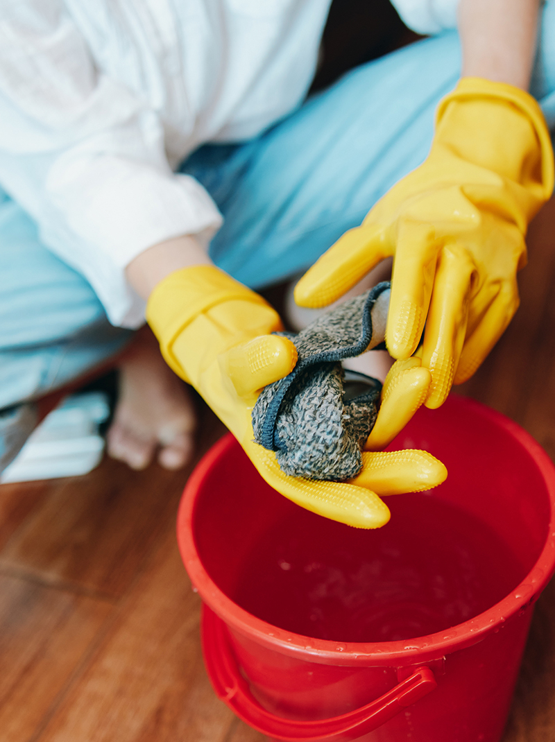 kädet kumihansikkaissa puristavat rättiä ämpäriin